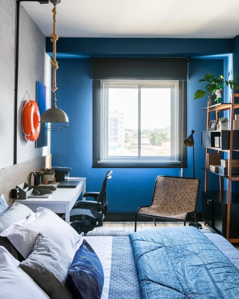 Vista do quarto do Decora, com cama, bancada e a peça em metacrilato na parede lateral.